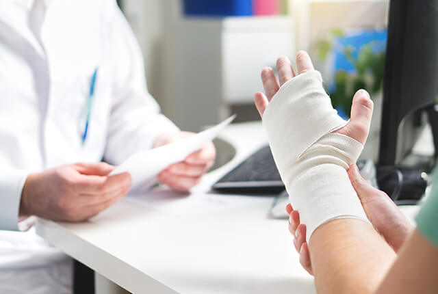 左手を怪我した患者を診察する男性医師