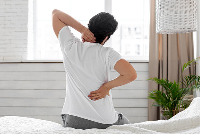 首と背中をおさえる男性