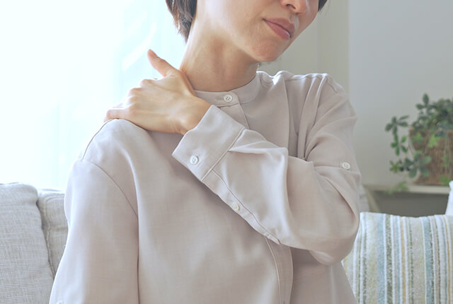 右肩を左手でおさえる女性