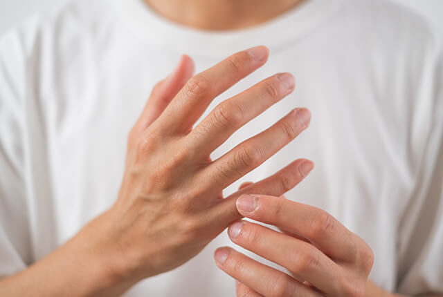 右小指を左手でおさえる男性