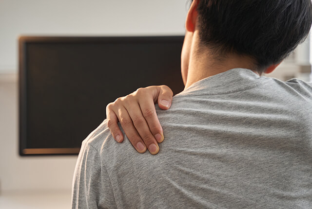 左肩を右手でおさえる男性