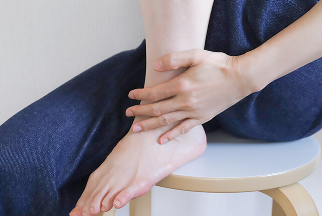 左足首を左手でおさえる女性