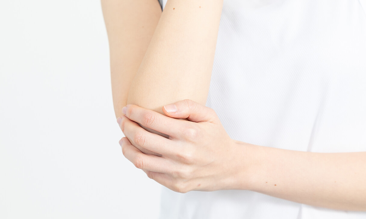 右肘を左手でおさえる女性