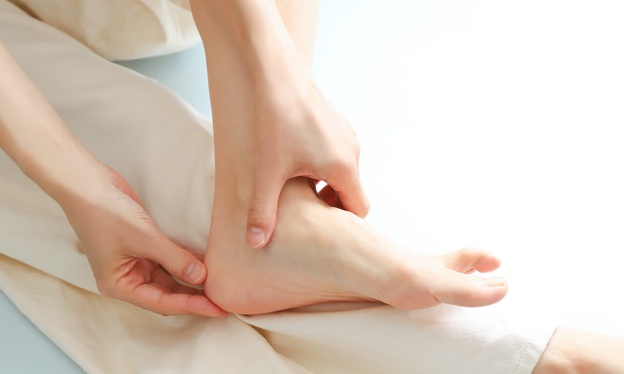 左足を左手でおさえる女性