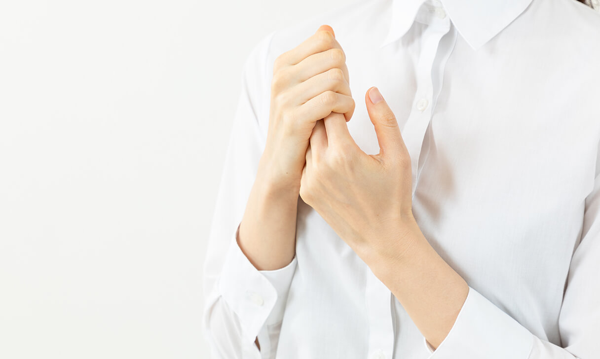 右手で左手を握る女性